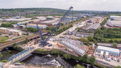 Reidsteel prefabricated steel through truss bridge is swung into place with the help of an 850T mobile crane